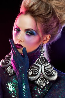 Parlak sanat-makyaj, mor tonlarda genç çekici sarışın kız. Rhinestones ve glitter vücut boyama.