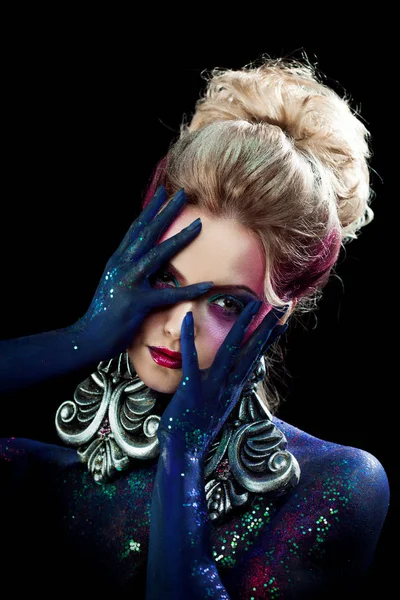 Young attractive blonde girl in bright art-makeup, clasped hands a head. Rhinestones and glitter body painting. — Stock Photo, Image