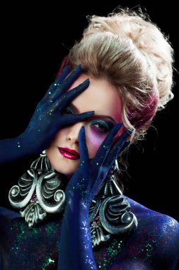 Genç çekici sarışın kız olarak parlak sanat-makyaj, Birleşmiş bir baş eller. Rhinestones ve glitter vücut boyama.