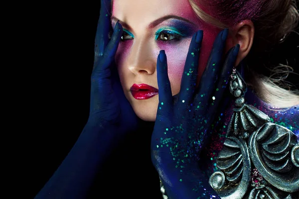 Attraktiva flicka i ljusa konst-makeup, knäppta händer ett huvud. Strass och glitter kroppsmålning. — Stockfoto
