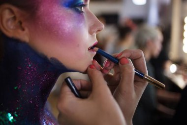 Makyaj sanatçısı dudaklarını boyar. Genç çekici sarışın kız olarak parlak sanat-makyaj.