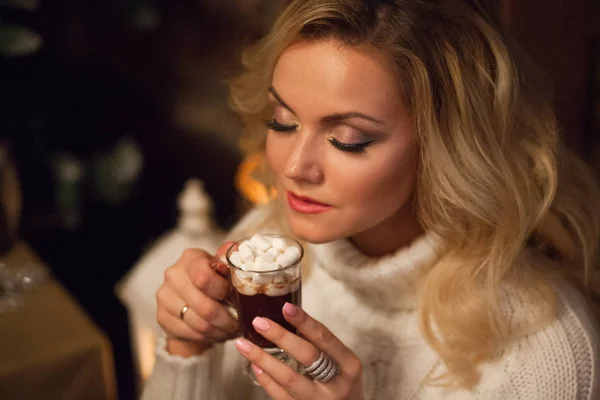 Vrolijk kerstfeest. Jonge vrouw gekleed hartelijk, warme chocolademelk drinken. — Stockfoto