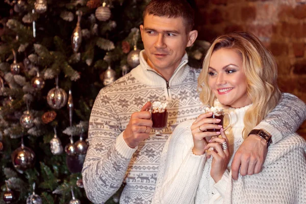 Veselé Vánoce. Mladý pár slaví Nový rok doma. Muž a žena pít kakao — Stock fotografie