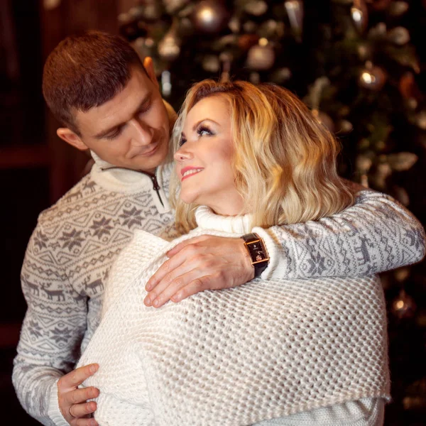 Pareja joven celebrando Año Nuevo en casa. Hombre y mujer abrazándose en el fondo del árbol de Navidad —  Fotos de Stock