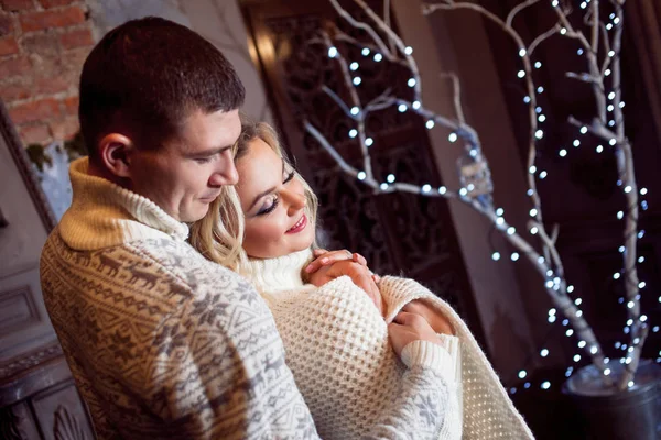 Pareja joven celebrando Año Nuevo en casa. Hombre y mujer abrazándose en el fondo del árbol de Navidad —  Fotos de Stock