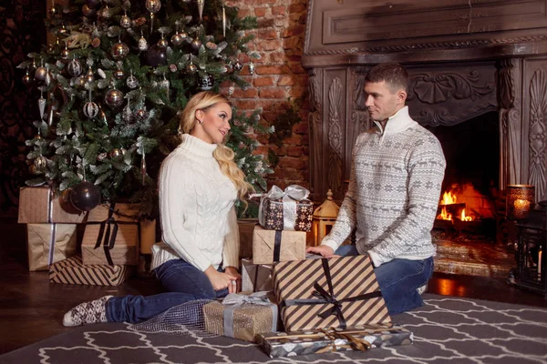 Jeune couple examine les cadeaux sous l'arbre de Noël. Vacances — Photo