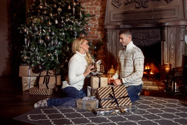 Et ungt par undersøker gavene under juletreet. Ferie – stockfoto