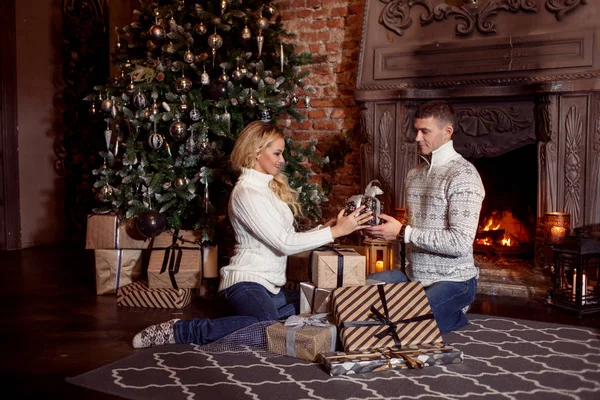 Young couple examines the gifts under Christmas tree. Holiday — Stock Photo, Image