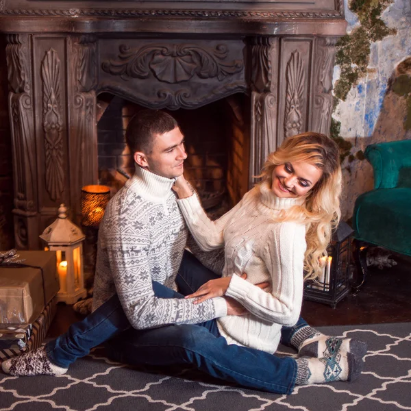 God Jul. Unga par firar nyår hemma. Man och en kvinna vid den öppna spisen — Stockfoto