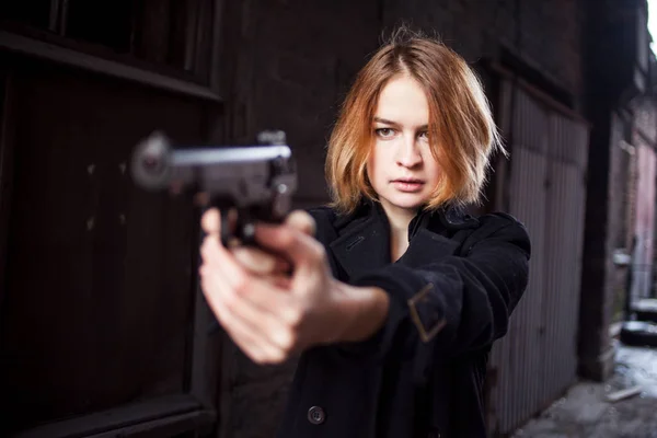 Mujer apuntando con un arma. Mafia chica disparando a alguien en la calle . — Foto de Stock