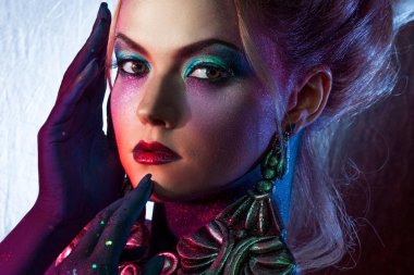 Parlak sanat-makyaj, yüksek saç, vücut boyama genç çekici sarışın kız. Rhinestones ve glitter