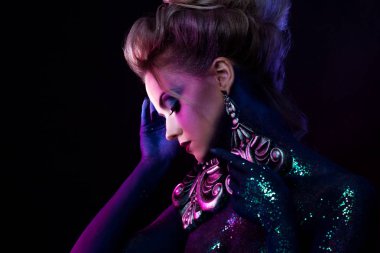 Parlak sanat-makyaj, mor tonlarda genç çekici sarışın kız. Rhinestones ve glitter vücut boyama.