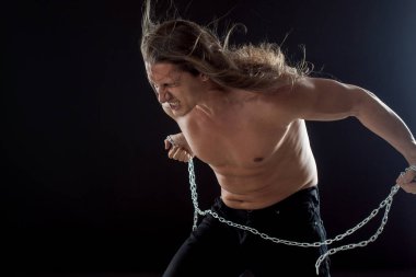 Uzun saçlı genç adam Demir zinciri keser. Güçlü. Direnç kavramı