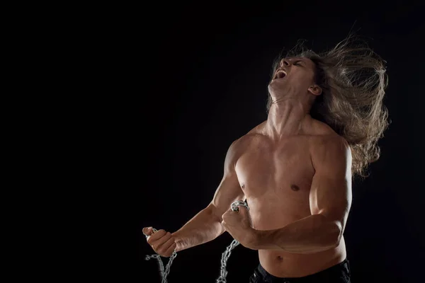 Young man with long hair breaks the iron chain. Strong. Concept of resistance — Stock Photo, Image