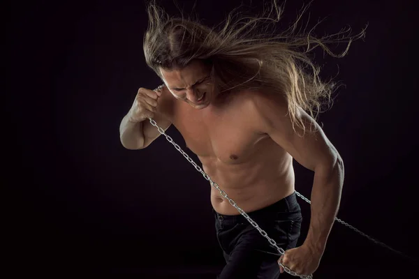 Joven con el pelo largo arrastrando algo detrás de él. Fuerte. . — Foto de Stock