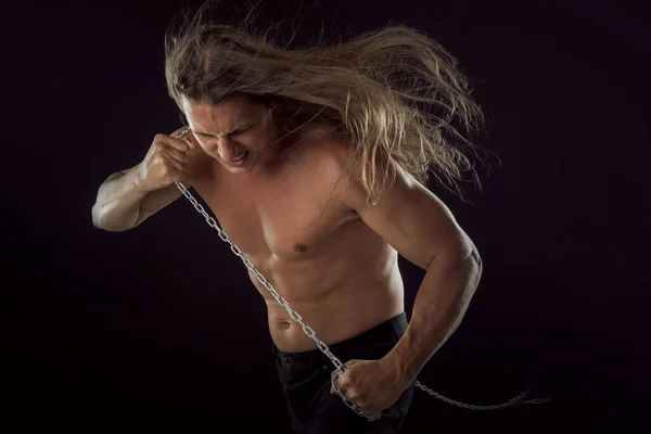 Young man with long hair dragging something behind him. Strong. — Stock Photo, Image