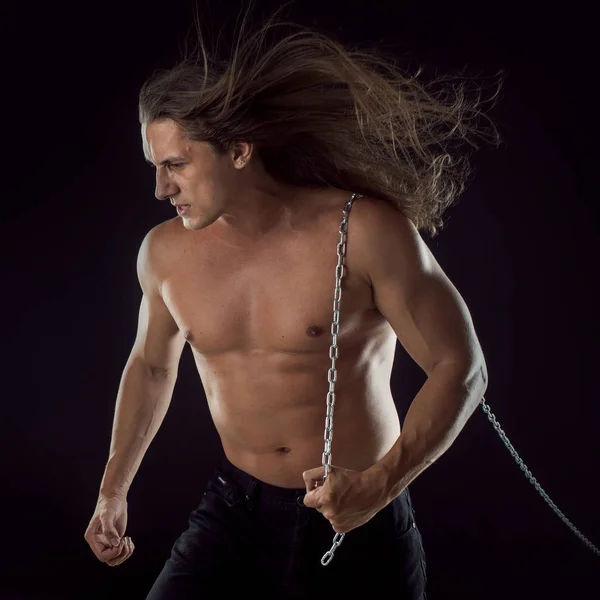 Joven con el pelo largo arrastrando algo detrás de él. Fuerte. . —  Fotos de Stock