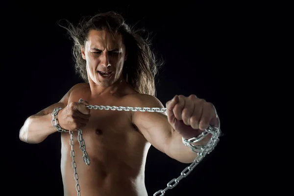 Young man with long hair breaks the iron chain. Strong. Concept of resistance — Stock Photo, Image
