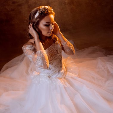 Güzel kız gelin oturan kat, portre altın tonlarda, parlama etkileri üzerinde lüks gelinlik