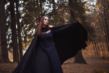 Genç güzel ve gizemli kadın ormanda hood, orman elf ya da cadı görüntü ile siyah pelerin