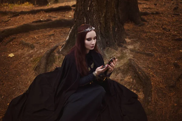 Young beautiful and mysterious woman image of forest elf or witch, looking in the mirror — Stock Photo, Image