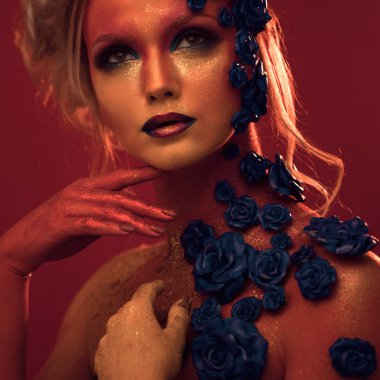 Sanat makyaj ile genç ve çekici bir kadın portresi. Ateşli renkler, parlak yüz ve çiçek dekorasyon