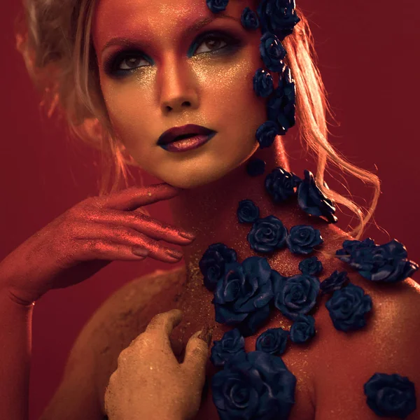 Retrato de mulher jovem e atraente com maquiagem de arte. Cores Fiery, brilho no rosto e decoração floral — Fotografia de Stock