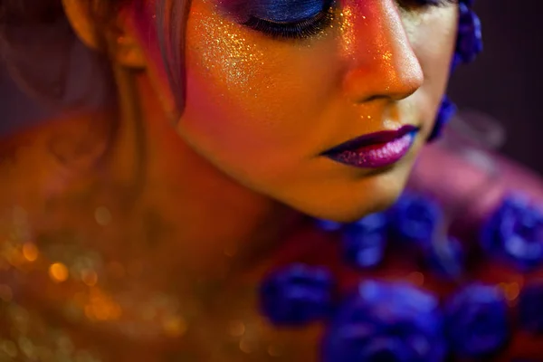 Retrato de mujer joven y atractiva con maquillaje artístico. Colores ardientes, brillo en la cara y decoración floral —  Fotos de Stock
