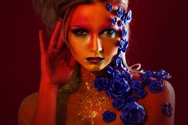 Sanat makyaj ile genç ve çekici bir kadın portresi. Ateşli renkler, parlak yüz ve çiçek dekorasyon