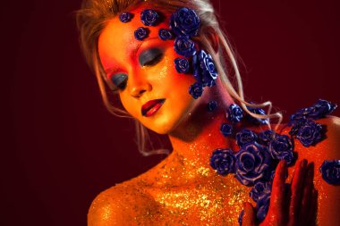 Sanat makyaj ile genç ve çekici bir kadın portresi. Ateşli renkler, parlak yüz ve çiçek dekorasyon