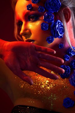 Sanat makyaj ile genç ve çekici bir kadın portresi. Ateşli renkler, parlak yüz ve çiçek dekorasyon
