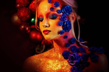 Sanat makyaj ile genç ve çekici bir kadın portresi. Ateşli renkler, parlak yüz ve çiçek dekorasyon