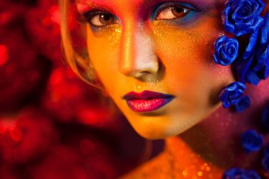 Sanat makyaj ile genç ve çekici bir kadın portresi. Ateşli renkler, parlak yüz ve çiçek dekorasyon