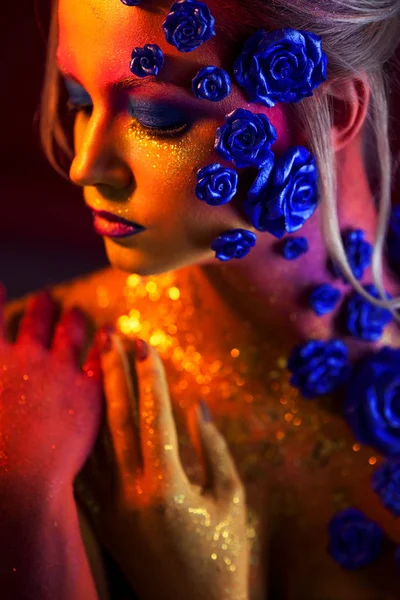 Portret van jonge, aantrekkelijke vrouw met kunst make-up. Vurige kleuren, glitter op gezicht en florale decoratie — Stockfoto
