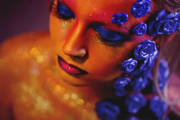 Sanat makyaj ile genç ve çekici bir kadın portresi. Ateşli renkler, parlak yüz ve çiçek dekorasyon