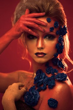 Sanat makyaj ile genç ve çekici bir kadın portresi. Ateşli renkler, parlak yüz ve çiçek dekorasyon