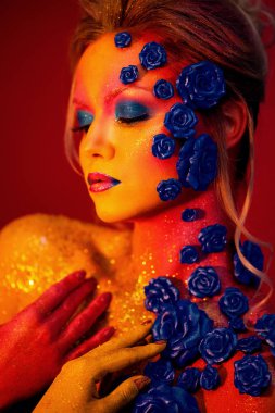 Sanat makyaj ile genç ve çekici bir kadın portresi. Ateşli renkler, parlak yüz ve çiçek dekorasyon