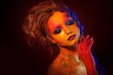 Sanat makyaj ile genç ve çekici bir kadın portresi. Ateşli renkler, parlak yüz ve çiçek dekorasyon