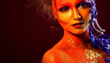 Sanat makyaj ile genç ve çekici bir kadın portresi. Ateşli renkler, parlak yüz ve çiçek dekorasyon