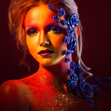 Sanat makyaj ile genç ve çekici bir kadın portresi. Ateşli renkler, parlak yüz ve çiçek dekorasyon