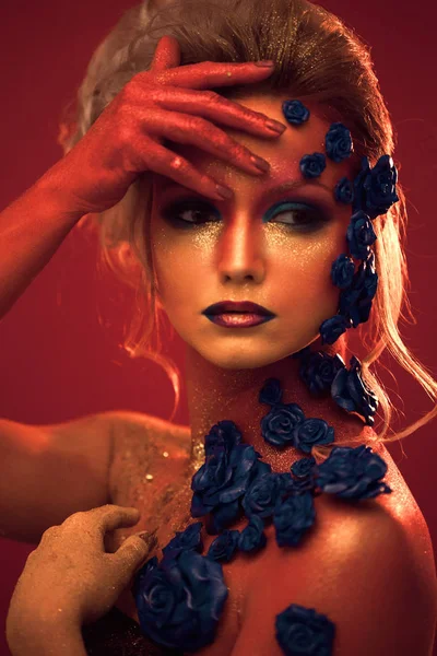 Sanat makyaj ile genç ve çekici bir kadın portresi. Ateşli renkler, parlak yüz ve çiçek dekorasyon