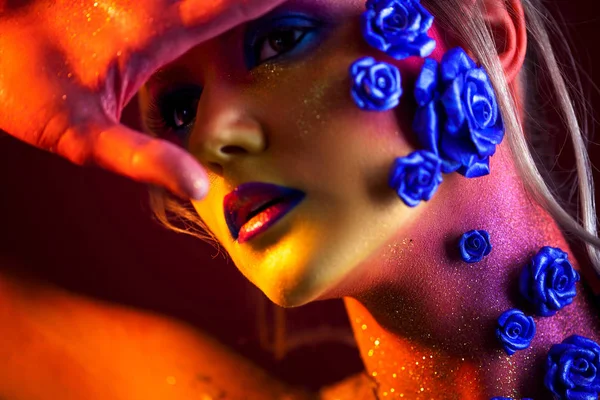 Portrét mladé a atraktivní žena s make-upem umění. Ohnivé barvy, třpytky na obličej a květinové dekorace — Stock fotografie