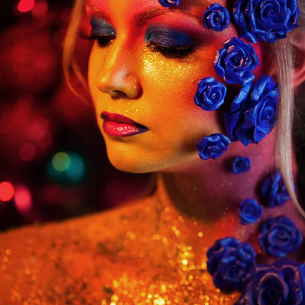 Portrait of young and attractive woman with art makeup. Fiery colors, glitter on face and floral decoration — Stock Photo, Image