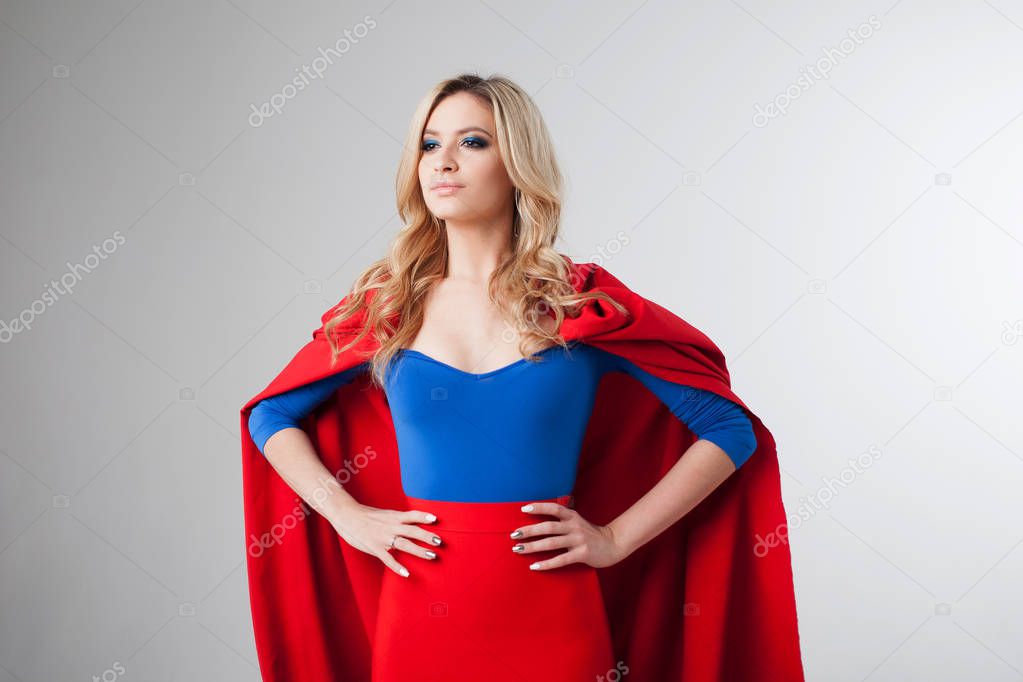 Superhero Woman. Young and beautiful blonde in image of superheroine in red Cape growing