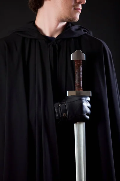 Portrait of a courageous warrior wanderer in a black cloak and sword in hand. — Stock Photo, Image