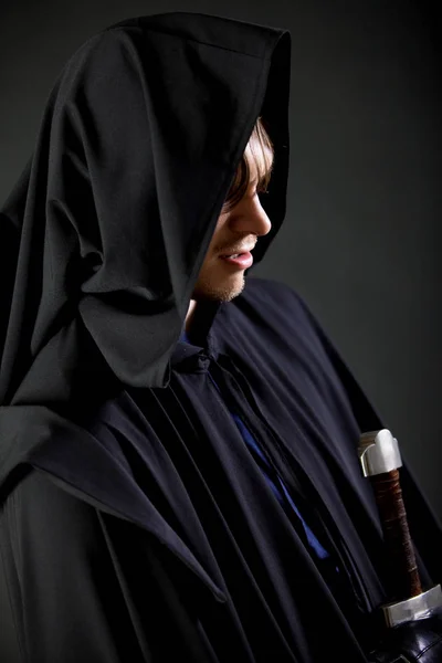 Portrait of a courageous warrior wanderer in a black cloak and sword in hand. — Stock Photo, Image