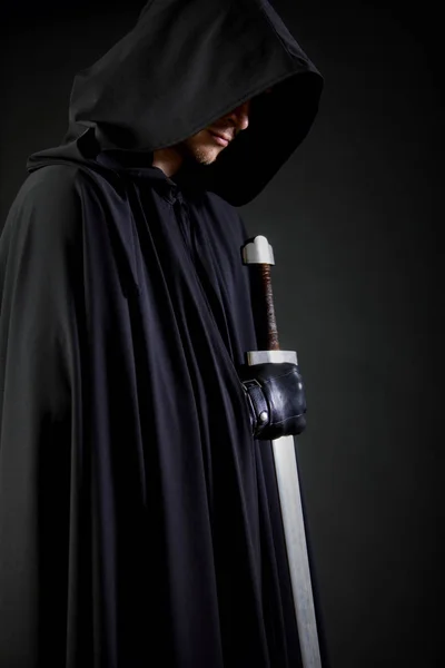 Portrait of a courageous warrior wanderer in a black cloak and sword in hand. — Stock Photo, Image