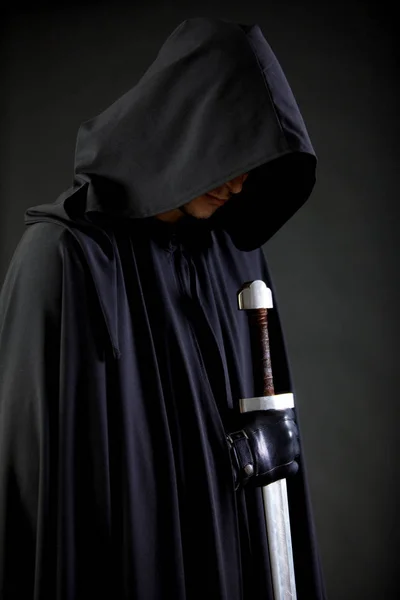 Porträt eines mutigen Kriegers in schwarzem Mantel und Schwert in der Hand. — Stockfoto