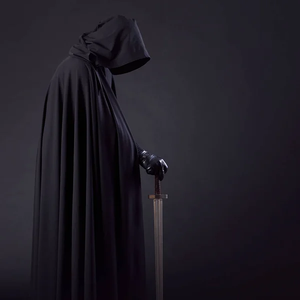 Portrait of a courageous warrior wanderer in a black cloak and sword in hand. — Stock Photo, Image