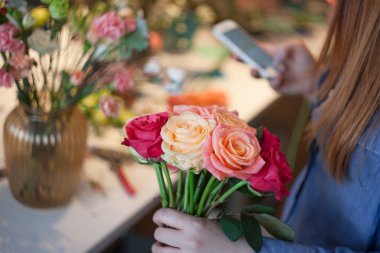 Atölye çiçekçi, buketler ve çiçek düzenlemeleri yapma. Bir buket gül toplama kadın. Yumuşak odak